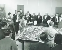  ?? COURTESY ?? Jim Rouse, center, with arms folded, presents plans for Columbia, as well as a model of Town Center and the first village, to the Howard County commission­ers and other county officials on Nov. 11, 1964.