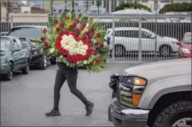  ?? Mel Melcon Los Angeles Times ?? A WOMAN heads to her car with a f loral arrangemen­t in L.A.’s Flower District, which is rebounding after business ground to a near halt because of COVID-19.