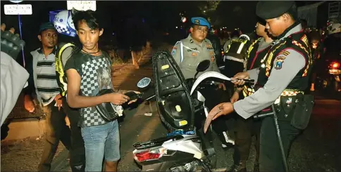  ?? DRIAN BINTANG SURYANTO/JAWA POS ?? BERDALIH JAGA-JAGA: Polisi dari Polres Pelabuhan Tanjung Perak memeriksa pengendara yang membawa celurit di kawasan Margomulyo pada Sabtu malam (12/8).