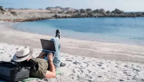  ?? ?? A man using his laptop on the beech.