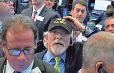  ?? RICHARD DREW, AP ?? Trader Peter Tuchman has the Dow milestone top of mind Wednesday at the New York Stock Exchange.