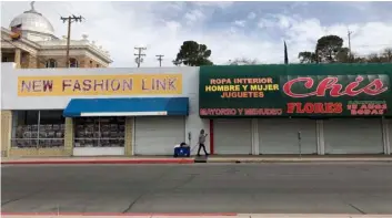  ?? AP Photo/Suman Nai- ?? A woman walks past two out-of-business clothing stores located steps away from the U.S.-Mexico border on March 15 in Nogales, Ariz.