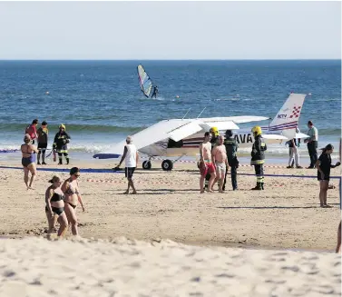  ?? ARMANDO FRANCA / THE ASSOCIATED PRESS ?? People walk past a plane parked by the sea after an emergency landing at Sao Joao beach in Costa da Caparica, Portugal, on Wednesday. The landing on the packed beach killed a man and a child who were sunbathing.