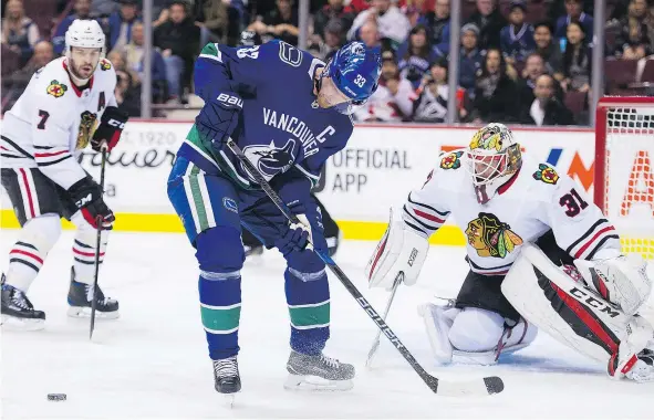  ?? GERRY KAHRMANN/PNG ?? Henrik Sedin tries to corral the puck while veteran Blackhawks defenceman Brent Seabrook looks on last Thursday night. The veteran Seabrook was recently benched as Chicago coach Joel Quennevill­e looked to send a message to his struggling team.