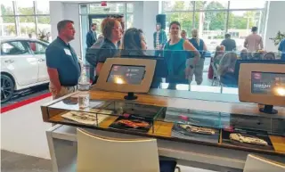  ??  ?? Mountain View Nissan of Dalton on Thursday marked the opening of its new store. People in the showroom mingle in front of design tablets on which customers can pick the features on their new car.