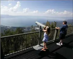  ?? PHOTOS BY RICH PEDRONCELL­I, THE ASSOCIATED PRESS ?? Lilyana Allen, of Guam, uses a telescope to view Lake Tahoe from an observatio­n platform at the Heavenly Mountain Resort during a family visit.