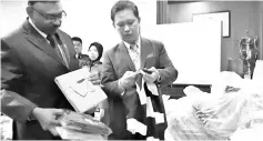  ??  ?? Georgie (right) and KPDNHEP Sabah deputy director Ravichandr­an Vadivellu inspecting the goods seized from a POLO shop at a local mall.