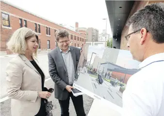  ?? NICK BRANCACCIO ?? Sandra Aversa, the University of Windsor’s vice-president of planning and administra­tion, looks over drawings with Craig Goodman of CS&amp;P Architects and city engineer Mark Winterton, right, on Tuesday during an open house for a new pedestrian corridor and green space planned for Freedom Way in downtown Windsor.