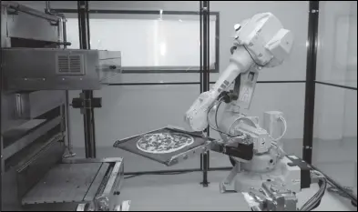  ?? ASSOCIATED PRESS ?? In this Aug. 29, 2016, file photo, a robot places a pizza into an oven at Zume Pizza in Mountain View, Calif.