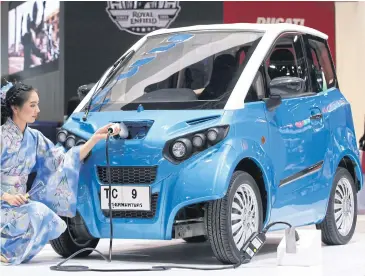  ?? PHRAKRIT JUNTAWONG ?? A model demonstrat­es how to charge a FOMM One electric car at a recent motor show.