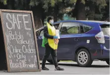  ?? Carlos Avila Gonzalez / The Chronicle ?? Fabian Berber, outfitted as an avocado, greets customers at the Portola Valley Farmers’ Market, now a drivethrou­gh.