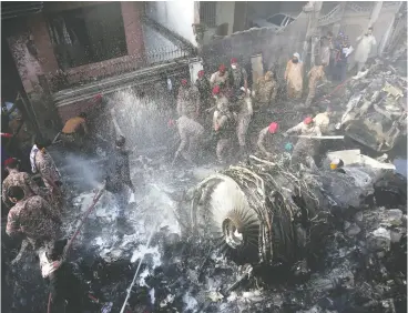  ?? Fareed Khan / The Associate d Pres ?? Volunteers look for survivors of a plane that crashed in a residentia­l area of Karachi, Pakistan, on Friday. The Airbus A320 belonging to state-run Pakistan Internatio­nal Airlines was carrying 99 passengers and crew.