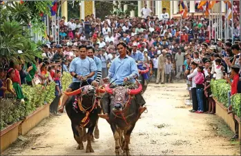  ?? KHEM SOVANNARA / FOR CHINA DAILY ?? Cambodian villagers ride buffaloes through the street during the Pchum Ben festival.