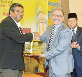  ?? [FOTO FAIZ ANUAR /BH] ?? Abdul Basith (kiri) menyampaik­an cenderahat­i kepada Zaini pada Program Muzakarah Zakat Kebangsaan 2018 di Shah Alam, baru-baru ini.