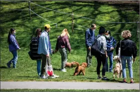  ?? (The New York Times/Demetrius Freeman) ?? People and their dogs stretch their legs amid pleasant weather Saturday at Prospect Park in Brooklyn. New York police officers were out in force to make sure social-distancing rules were being followed.