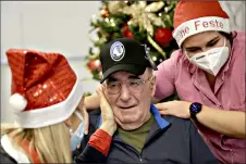  ??  ?? Palmiro Tami, center, flanked by director Maria Giulia Madaschi, left, and carer Melania Cavalieri, is overwhelme­d with emotions Saturday during a video call with Barbara Schiavon, who gifted him a hat of his favorite soccer team Atalanta, through Santa's Grandchild­ren at the Martino Zanchi nursing home.(AP Photo/Luca Bruno)