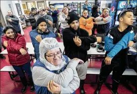  ?? BONNIE JO MOUNT PHOTOS / WASHINGTON POST ?? New employees, including Gretchen Velez (left), 21, participat­e in a stretching exercise during orientatio­n at Dakota Provisions in Huron, South Dakota, in December.