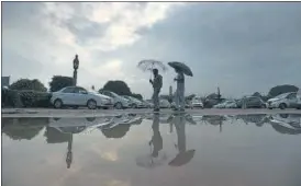  ??  ?? Pedestrian­s carry umbrellas at Vijay Chowk on a rainy evening in New Delhi on Monday.the Capital is likely to witness a light spell of rainfall on Tuesday as well, IMD said.