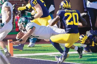  ?? CARLOS OSORIO/ASSOCIATED PRESS ?? Michigan State running back Connor Heyward dives over the goal line for a touchdown in the second half vs. Michigan in Ann Arbor. The underdog Spartans stunned the host Wolverines 27-24.