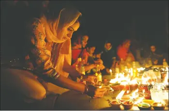  ??  ?? Above: Soni Gil of Lathrop lights candles during the Diwali celebratio­n at the Deshmesh Darbar Sikh temple in Lodi on Thursday. Left: Baljit Kaur, of Stockton, and mom Jasminder and daughter Nikita Sahota, 13, light candles during the Diwali celebratio­n