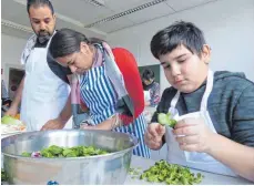 ??  ?? Die Jugend ist für den Salat zuständig. Wie der neunjährig­e Furkan (rechts), der penibel und geduldig jedes einzelne Würzelchen vom Feldsalat zupft.