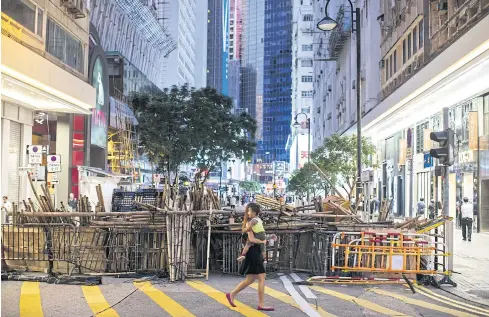  ?? BLOOMBERG ?? A pedestrian walks past barricades set up by demonstrat­ors on Patterson Street during a protest in the Causeway Bay district yesterday.