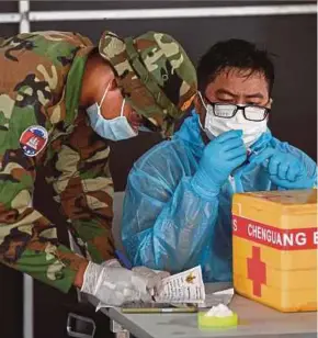  ?? AFP PIC ?? A military medical worker preparing a dose of the Sinovac Covid-19 vaccine at the Australian Centre for Education in Phnom Penh on Saturday.