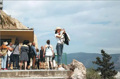  ?? YORGOS KARAHALIS / BLOOMBERG ?? A Chinese tourist uses a smartphone to record the view during a visit at the Acropolis archaeolog­ical site in Athens, Greece. Online travel agencies such as Priceline have been hoping to tap into China’s surging outbound tourism market.