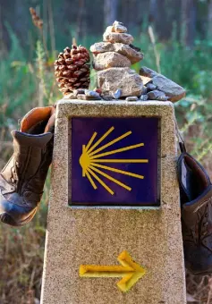  ??  ?? ON THE WAY: Hiking boots lie across a stone marker bearing the symbol of the Way of St James