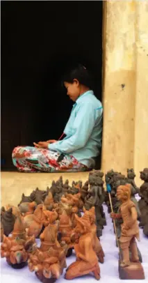  ??  ?? SOLITUDE. A Bagan woman with souvenir sculptures at one of the Buddhist temples.