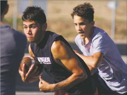  ?? Arcenio J. Trujillo ?? Questa senior Derek Vialpando (with ball) runs one of the options out of the “wildcat” formation during a workout at Questa High School Aug. 20. The football team, under the tutelage of first-year coach Daniel Gallegos is slowly building up their ranks as they prepare to start the 2018 season. Vialpando has been a part of the varsity football team since his freshman year and looks ready to lead the Wildcats forward after a rough, two-year patch.