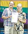  ?? Arkansas Democrat-Gazette file photo ?? John Schenk (left) and Robert
“Bobby” Loyd hold their marriage license in front of their Pink House on June 26, 2015, after the Supreme Court legalized same-sex marriage. The couple were married in Faulkner County.