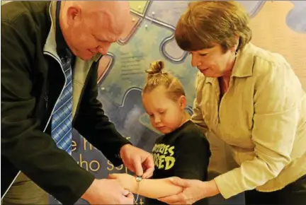  ?? TANIA BARRICKLO-DAILY FREEMAN ?? Town of Ulster Police Lt. Kyle Berardi, left, demonstrat­es how a MedicAlert ID can be placed on a child’s wrist. Above, Keegan SmithAuchm­oedy, a child at the Center for Spectrum Services with autism, would be a candidate for an ID bracelet. Holding him...