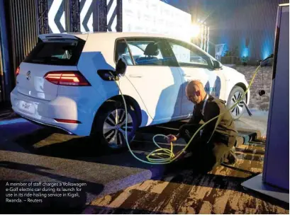  ??  ?? A member of staff charges a Volkswagen e-golf electric car during its launch for use in its ride-hailing service in Kigali, Rwanda. — Reuters