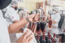  ?? LOUREIRO FERNANDEZ/THE NEW YORK TIMES ADRIANA ?? Jose Colbi, a rehabilita­ted gang member, seals bottles at the Santa Teresa rum factory in Sabaneta, Venezuela, in August. The family that owns the company is giving gangsters a life outside of crime.