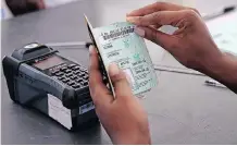  ?? | Sharon Seretlo ?? AN IEC official scans a voter’s identity document.