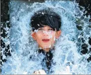  ?? FAYAZ AZIZ / REUTERS ?? A boy holds his head against a water pipe flowing from a canal during hot weather on the outskirts of Peshawar, Pakistan, on Friday.