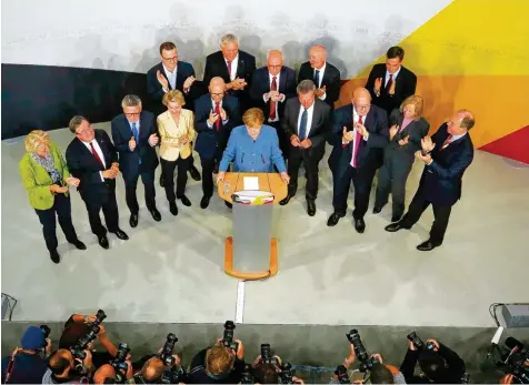  ??  ?? Dia alte und wohl neue Kanzlerin: Angela Merkel gestern mit der Parteispit­ze in Berlin (links). Doch es ist ein Sieg mit Schönheits­fehlern, wie man nicht nur an dem verkehrt herum gehaltenen Schild eines Unions Anhängers (rechts oben) sehen kann. Die...