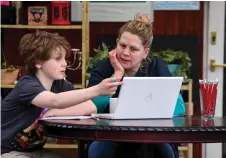  ?? — AFP photos ?? 11-year-old Lucas sits with his mother Fiona as she helps him with online lessons, set by his school following the national school closures due to the novel coronaviru­s pandemic, in Glasgow.