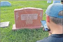  ?? [PETER ADAMS] ?? Volunteer Brayden Burke takes a picture of a headstone with his cell phone during Grant Lyon's BillionGra­ves Eagle Scout project at Trice Hill Cemetery in Forest Park.