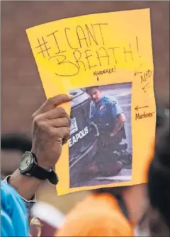  ??  ?? Un manifestan­te muestra una imagen del policía que asfixió a Floyd.