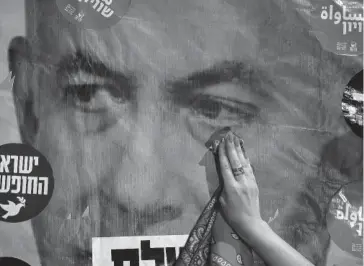  ?? AFP ?? > Manifestan­te israelí imita limpiando una lágrima de un cartel de Netanyahu.