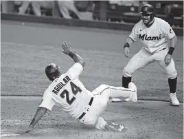  ?? DAVID SANTIAGO dsantiago@miamiheral­d.com ?? The Marlins’ Jesus Aguillar scores on a single by Brian Anderson as teammate Francisco Cervelli welcomes him home in the fourth inning Tuesday.