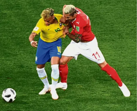  ?? — AFP ?? Shackled: Switzerlan­d midfielder Valon Behrami (right) tugging Brazil forward Neymar’s shirt during the Group E match at the Rostov Arena on Sunday.