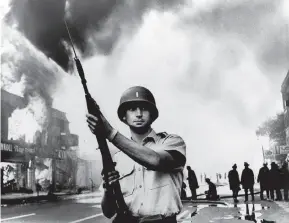  ?? Associated Press 1967 ?? A National Guardsman patrols a Detroit intersecti­on during the July 1967 riots. That summer, 150 cases of civil unrest erupted across the country.