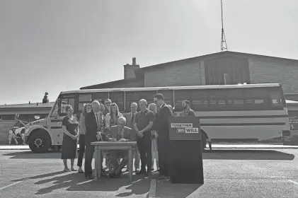  ?? PROVIDED BY JESSIE OPOIEN ?? Democratic Gov. Tony Evers signs a bill allowing school board members to volunteer as bus drivers in New Glarus, surrounded by lawmakers and district officials.