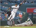  ?? MICHAEL CHOW/THE REPUBLIC ?? A’s Mark Canha (20) slides as D-Backs third baseman Eduardo Escobar (5) jumps for an errant throw during the first inning.