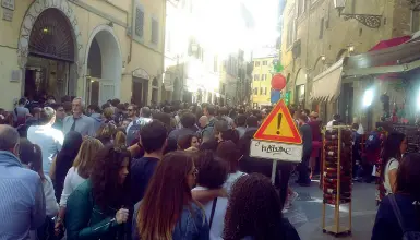  ??  ?? Sopra via dei Neri ieri invasa dai turisti A sinistra una volontaria che cerca di fare spazio a una macchina