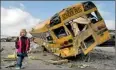  ??  ?? A girl walks past a destroyed school bus