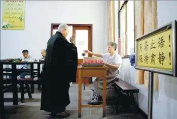  ?? PHOTOS BY GAO ERQIANG / CHINA DAILY ?? Top: Seniors eat lunch in the dining room at the Lingyansha­n Buddhist Nursing Home. Center: Elderly residents, all lay Buddhists, chant scriptures from 5 pm to 6 pm every day. Above: A resident collects a portion of fruit after lunch at the home.